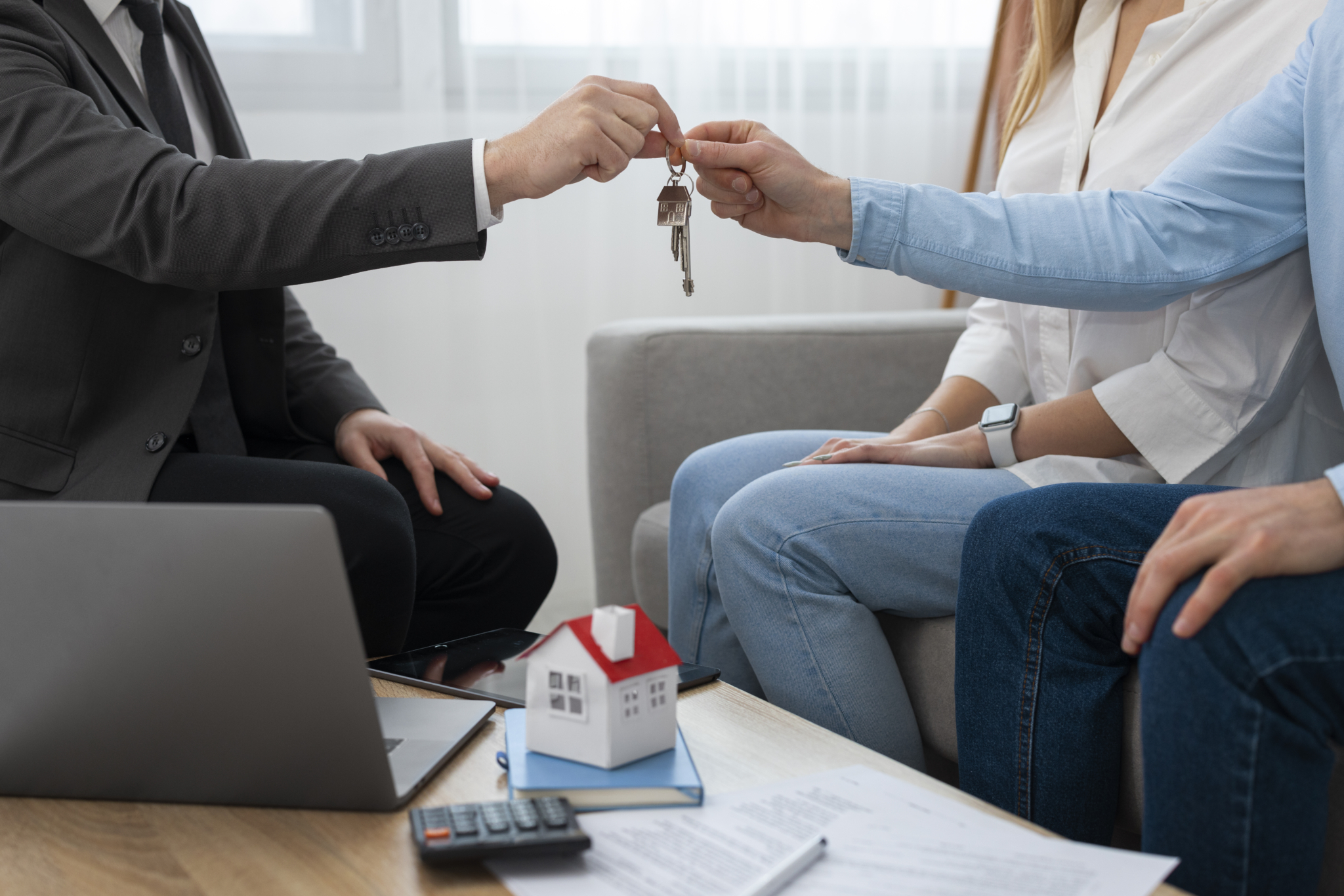 Property manager handing house keys to clients at a consultation table